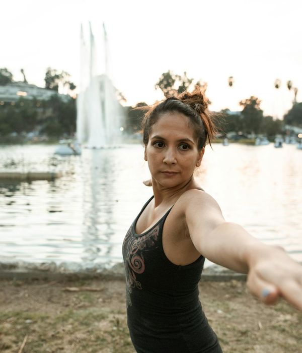 A woman in activewear stretching outdoors with a serene look.